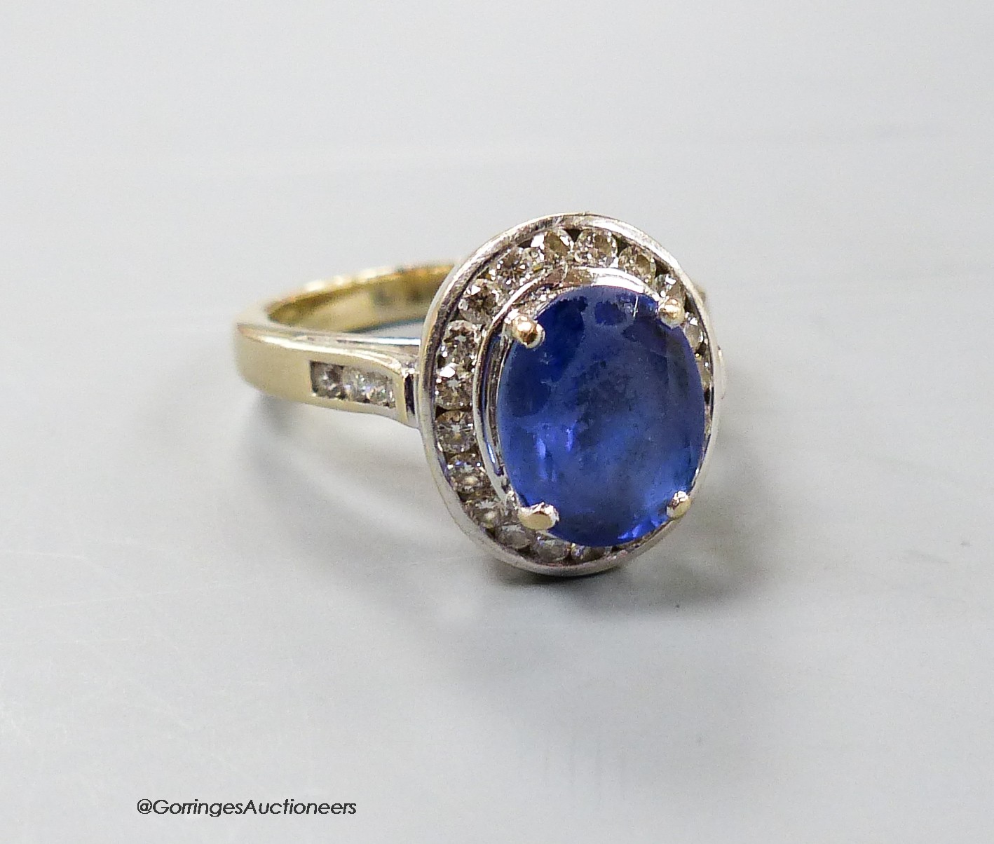 A modern 750 yellow metal, tanzanite and diamond chip oval cluster ring, size P, gross weight 9 grams